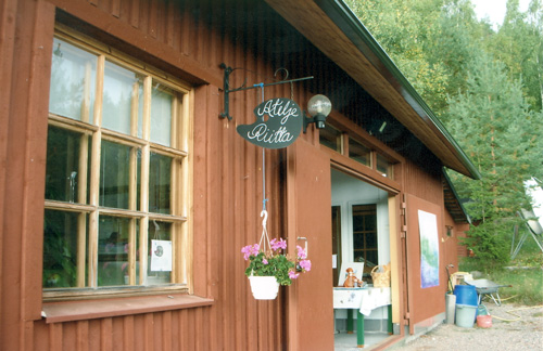 kuvassa puinen ruskea rakennus ja kyltti jossa lukee Atelje Riitta
