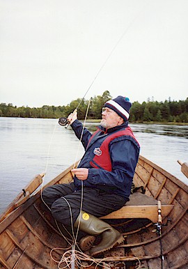valokuvassa mies istuu soutuveneessä ja heittää virveliä.