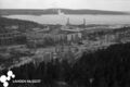 valokuva jossa ylhäältä päin kuvattu näkymä Nimen asuinalueelle ja satamaan jossa savua tupruttavia tehtaanpiippuja