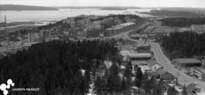 valokuvassa ilmakuva Kivimaan kaupunginosasta, kerrostaloja ja taustalla Vesijärven rantaa ja tehtaanpiippu satamassa.