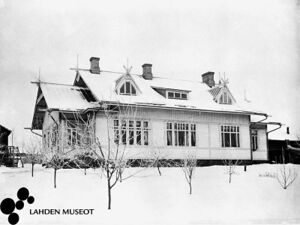 Kuvassa puinen, harjakattoinen Frostellin talo talvimaisemassa